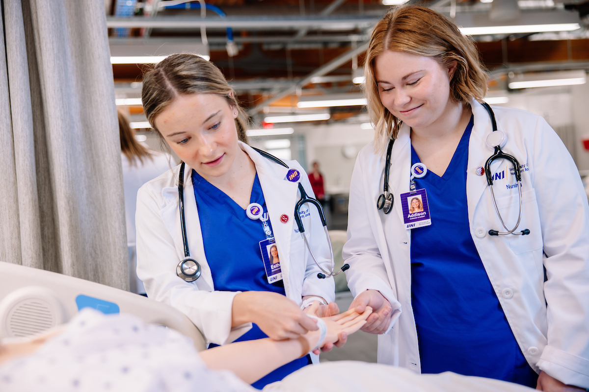 Nursing students check on simulated patient